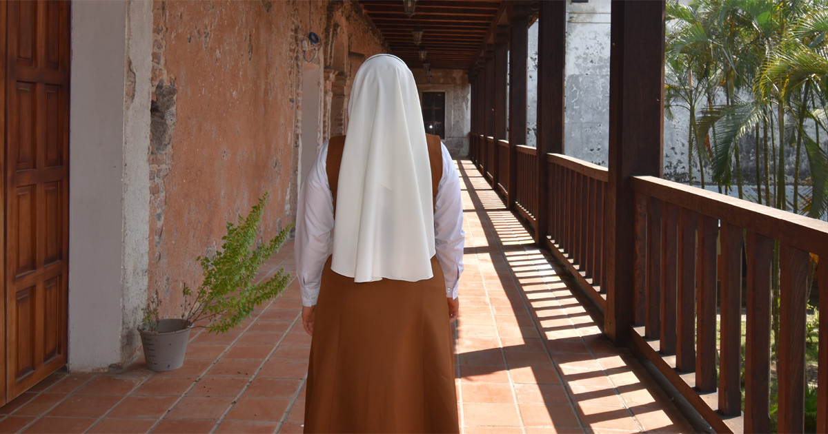 Nun, facing away, walking accross a porch