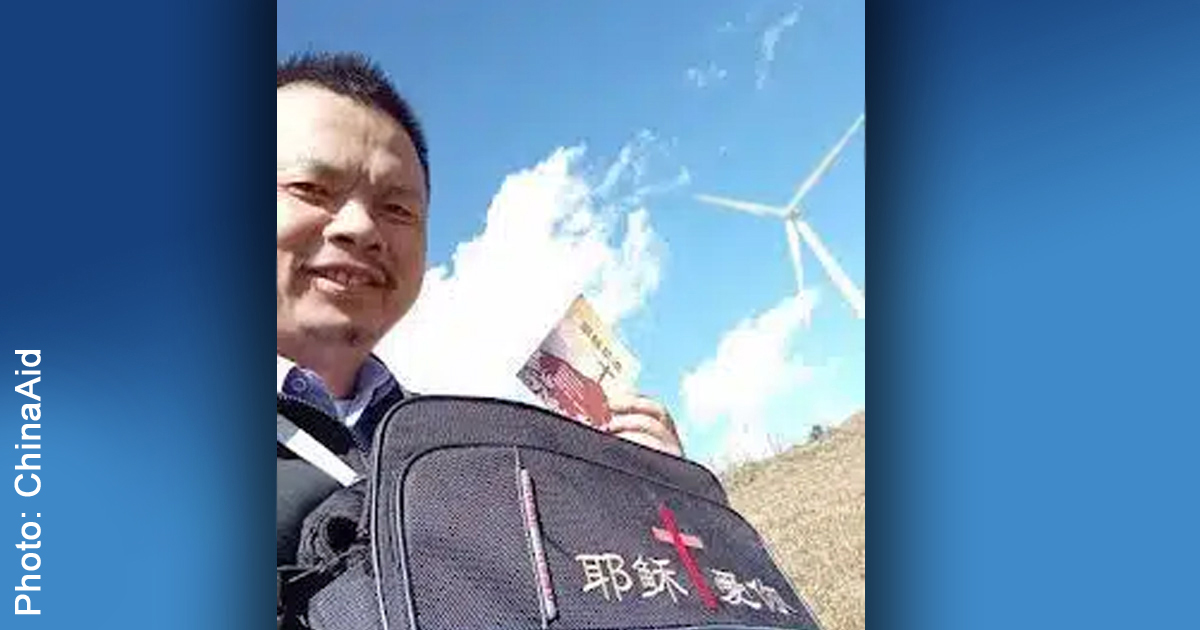 Chen Wensheng is smiling and holding a backpack and a piece of literature.