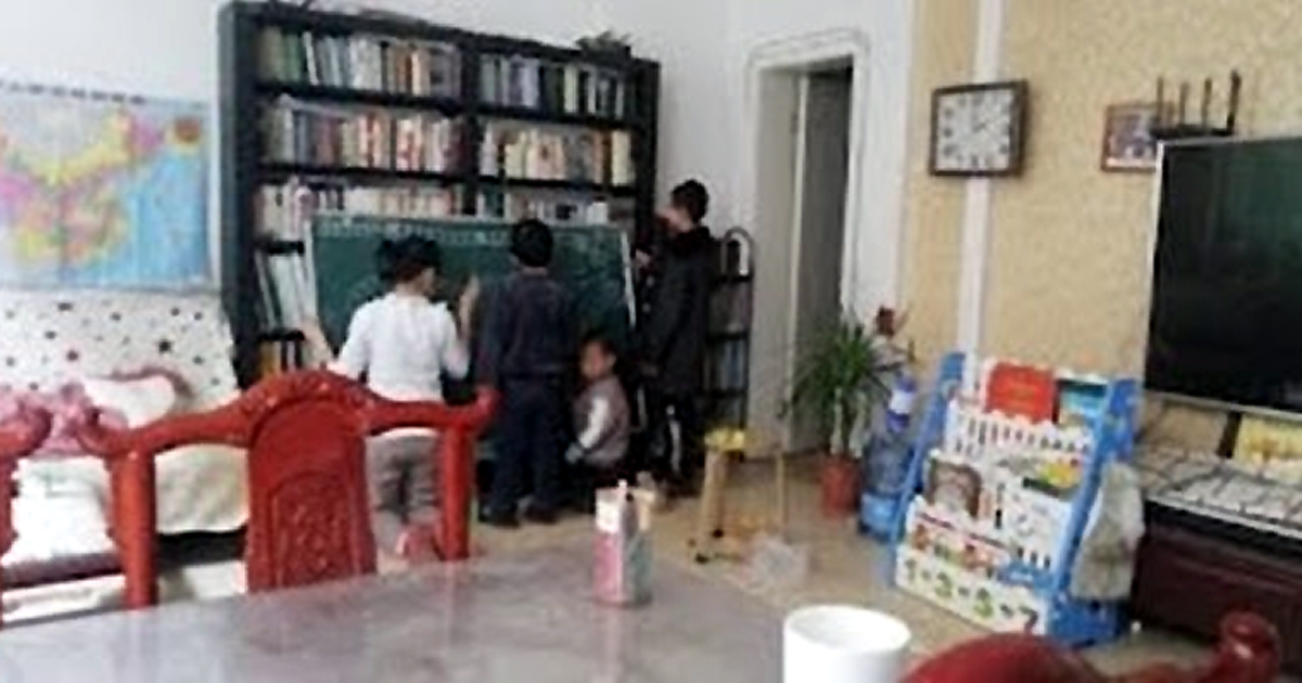 Three adults and a child inside a building, using a chalkboard.