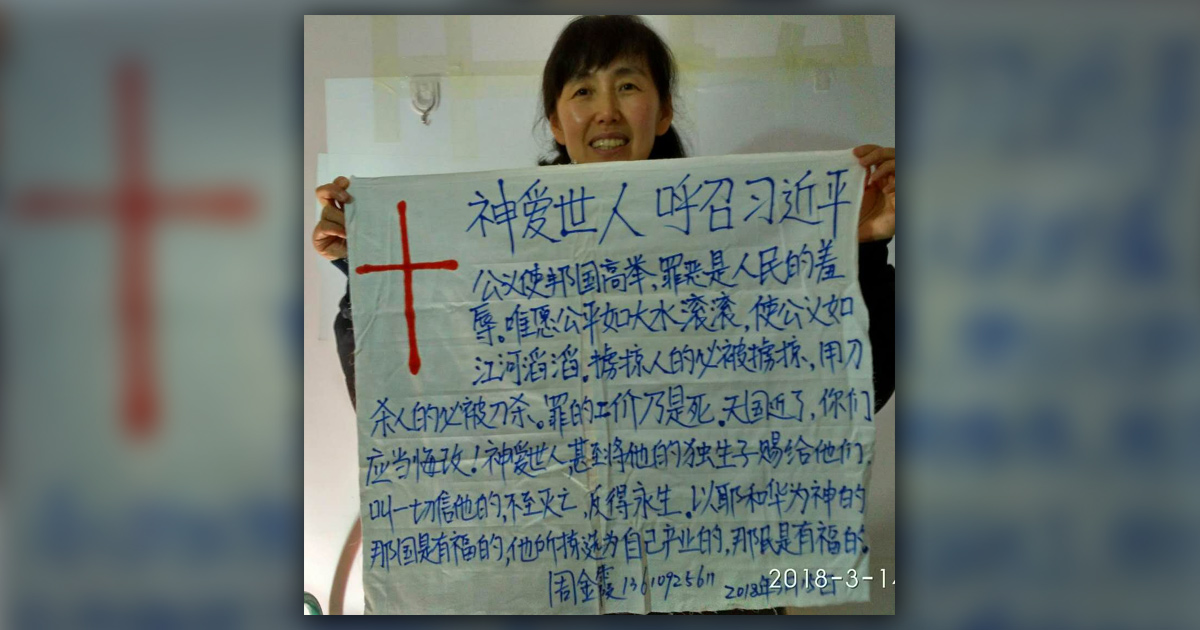 Zhou Jinxia smiling and holding her Gospel sign.