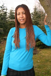 Helen Berhane is smiling as she leans against a tree.