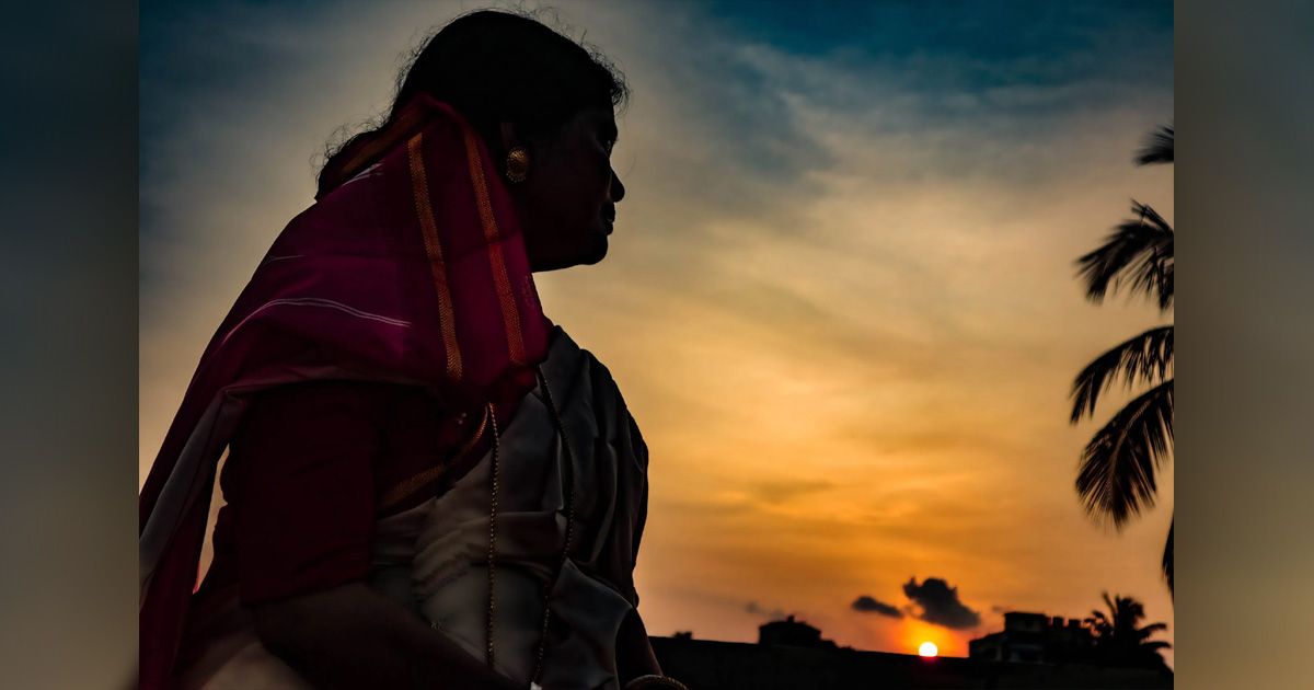 A woman is silhouetted against a sunset.