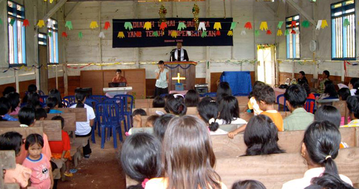 A congregation in church with a person at the pulpit.