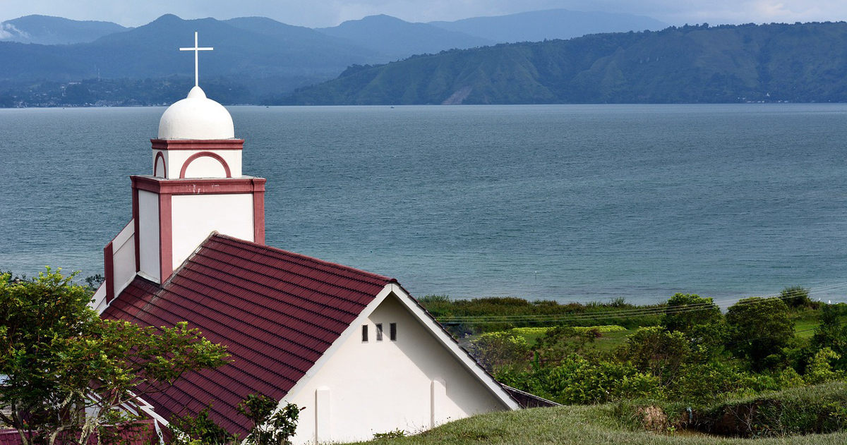 A church with water and hills in the background.