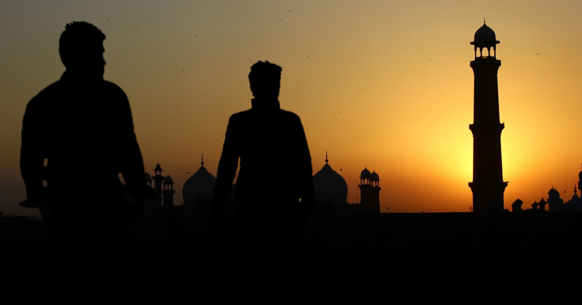 Two men are silhouetted against the outline of a mosque.