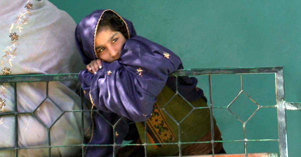 A girl is looking into the distance with her arm draped over a railing.