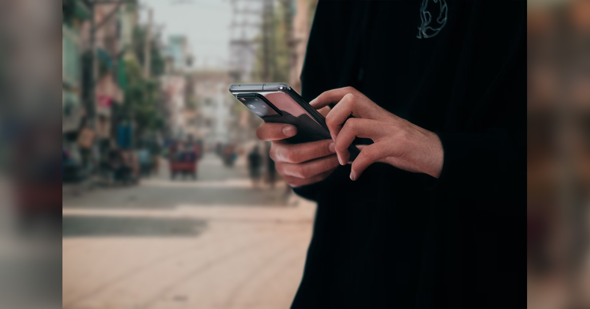 Woman holding a cell phone; city street in the background