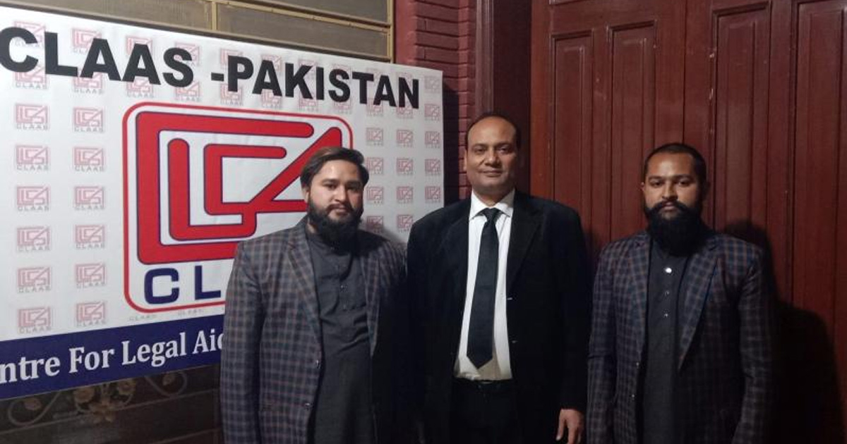 Raja and Rocky are standing with their attorney. A banner for CLAAS (Center for Legal Aid Assistance & Settlement) is on the wall behind them.