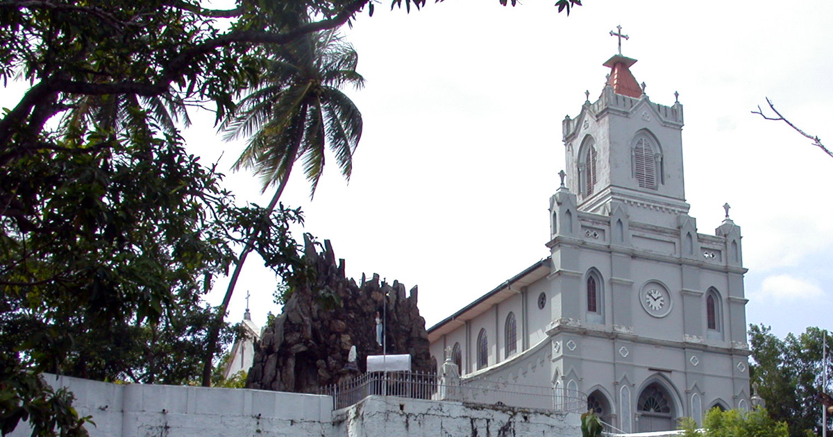 A large, white church with a cross atop of the steeple.