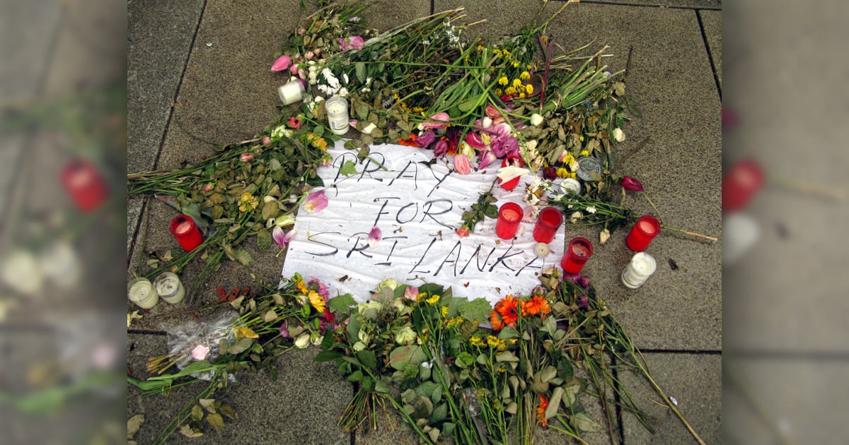 Flowers surrounding a poster saying, ''Pray for Sri Lanka''