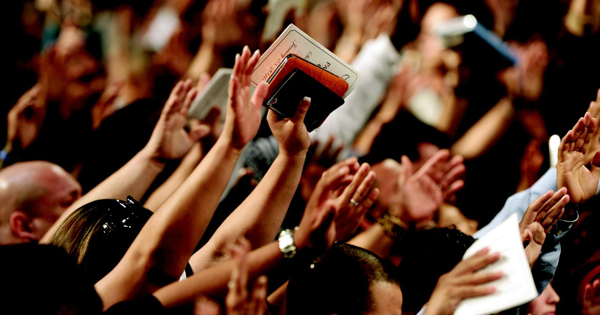 Many people have their hands raised in worship.